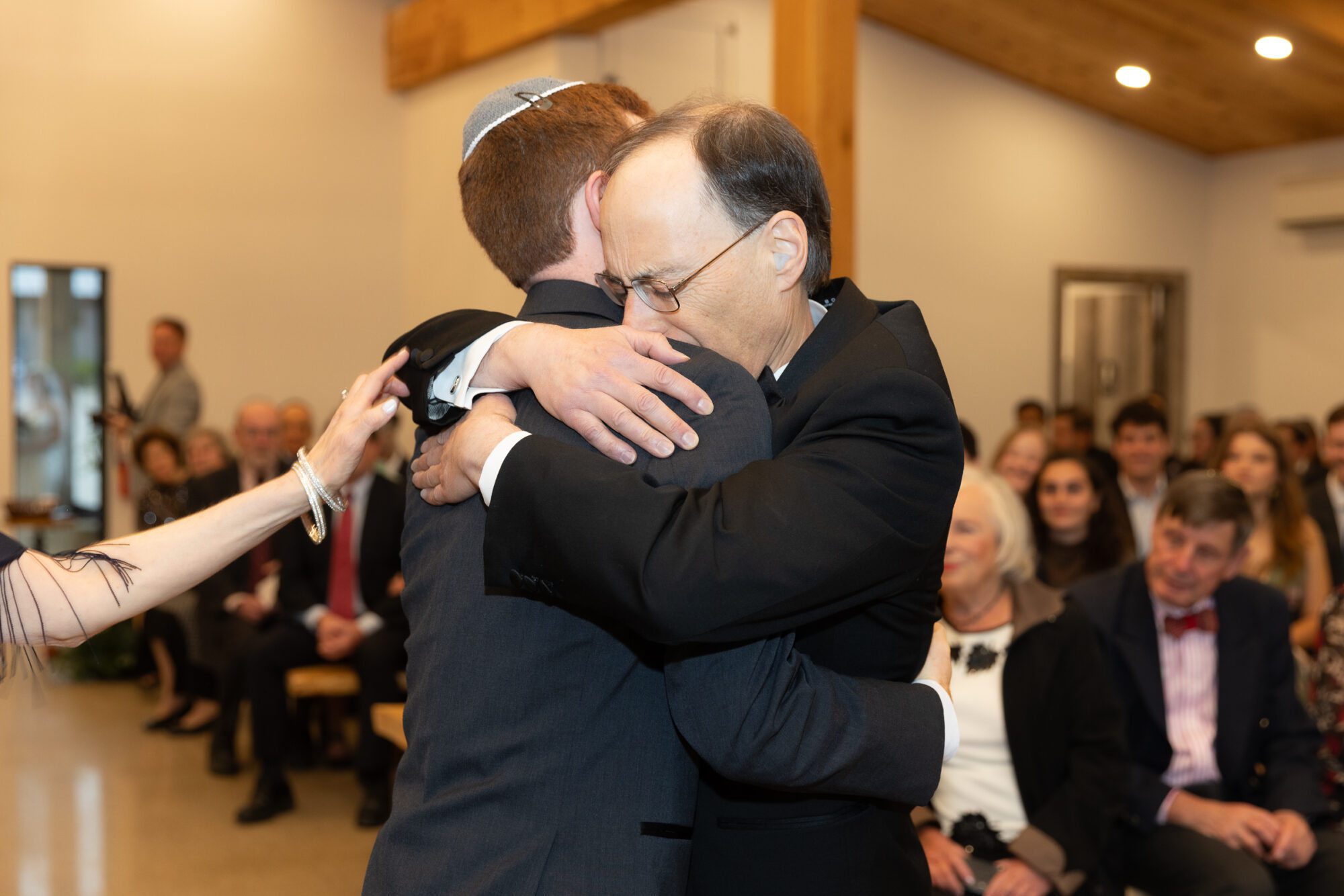 Jewish bride and groom's wedding ceremony. Father of groom cries while hugging groom.