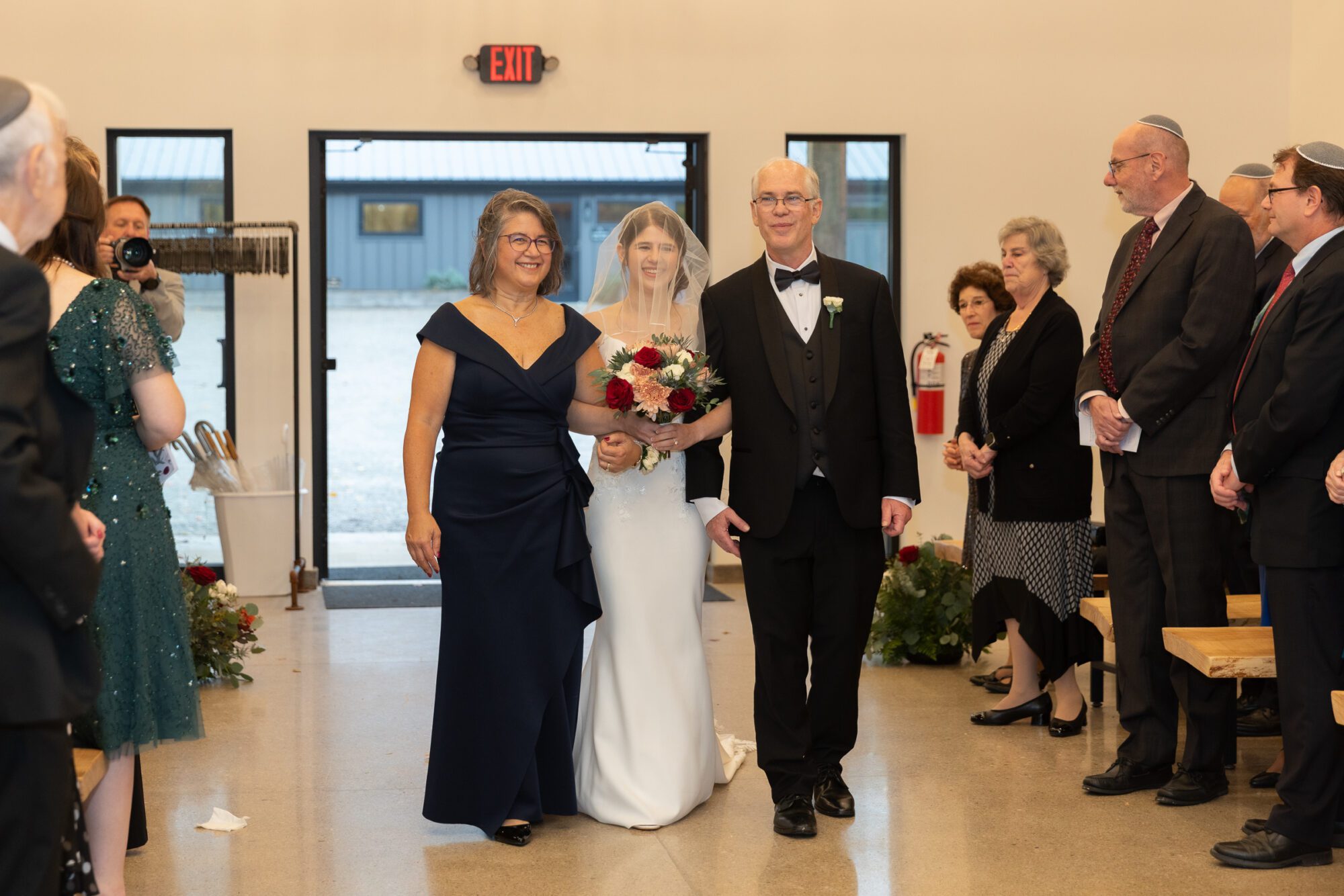 Jewish bride and groom's wedding ceremony. Bride walking down aisle with her parents.