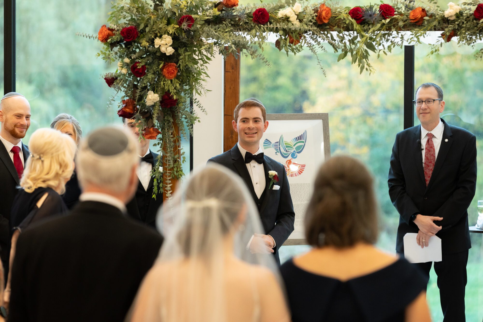 Jewish bride and groom's wedding ceremony. Groom watching bride walk down aisle.