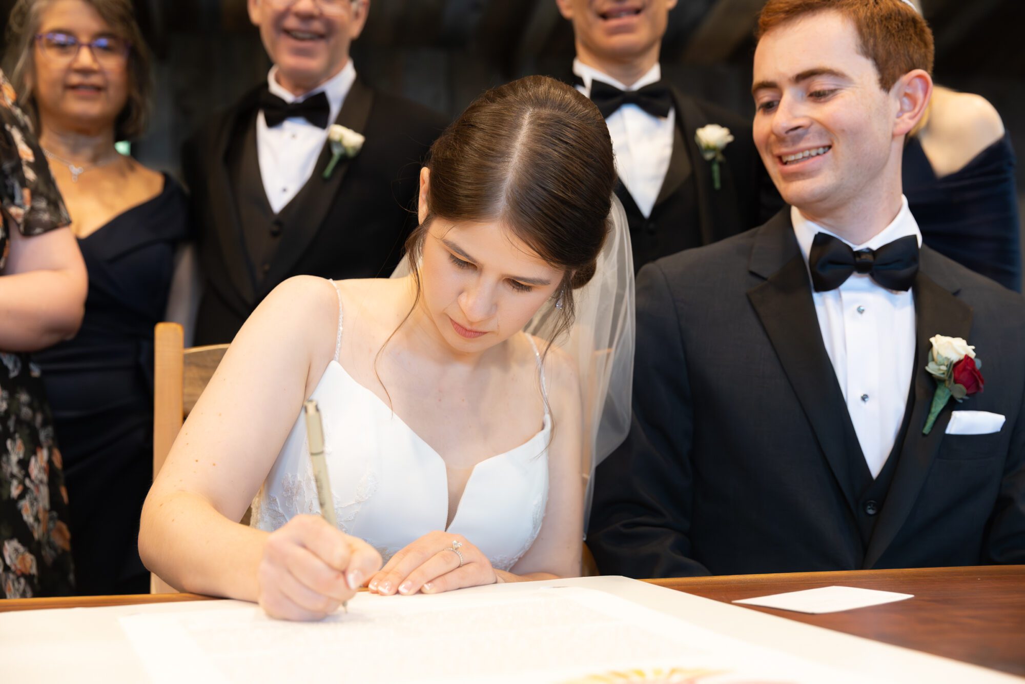 Jewish bride and groom's wedding ketubah signing ceremony. Bride signs ketubah.