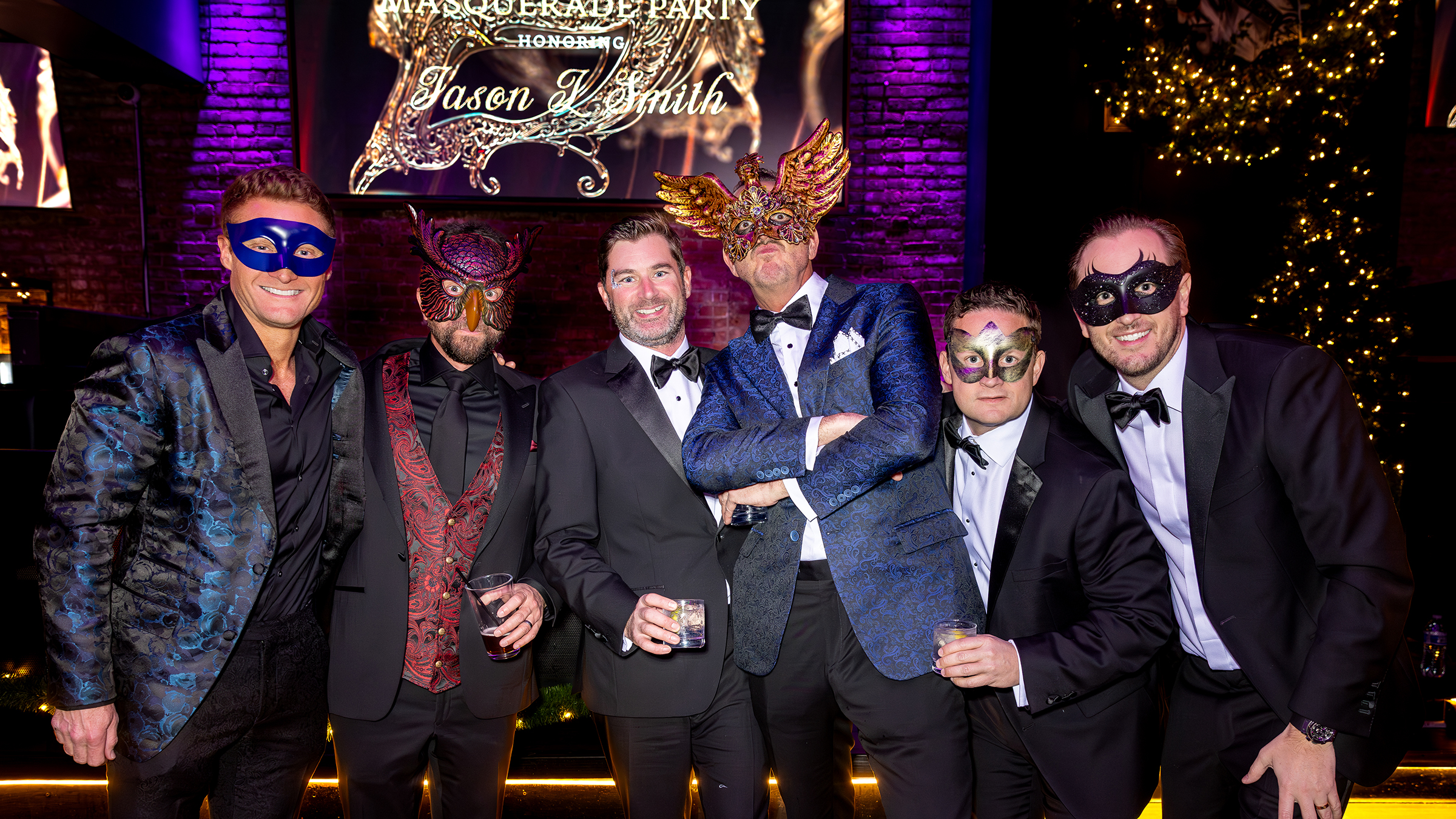 Six men in formal tuxedos and ornate masquerade masks at a birthday party at The IVY in Cleveland